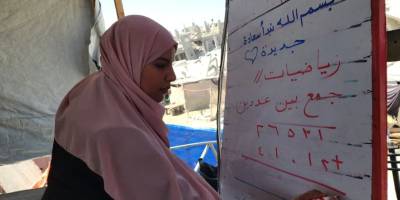 Filistinli öğretmen, evinin enkazında kurduğu çadırda çocuklara ders veriyor